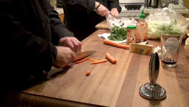 HAUTEMEALZ KITCHEN, PORTLAND, ORE. (November 6, 2013) While Chef Perry Perkins chops cilantro for his chicken sausage lettuce rolls, Chef Terry Ramsey cuts carrots. By squaring the sides of the carrots, Chef Terry creates a stable platform for chopping the root vegetable into planks and then matchsticks. As part of their lessons, the chefs explain these kitchen terms to their customers. Chef Perry adds, "We know when our customers have graduated from our service when they start arguing with us." Both men chuckle as they keep chopping. (Photo by Kaley Perkins / Independent Journalist)